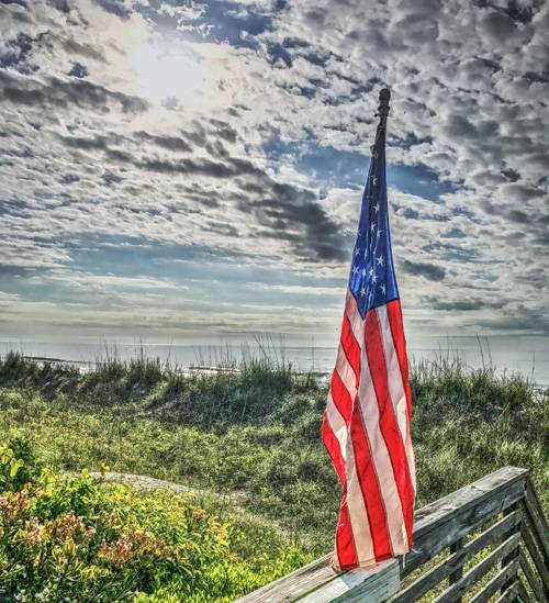 American Flag Posted on wooden stairs leading down to a beach