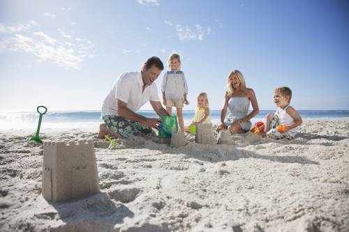Family of five building a sand castle in the sand